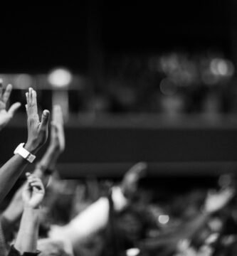 Black and white image of audience with hands raised, capturing concert energy.